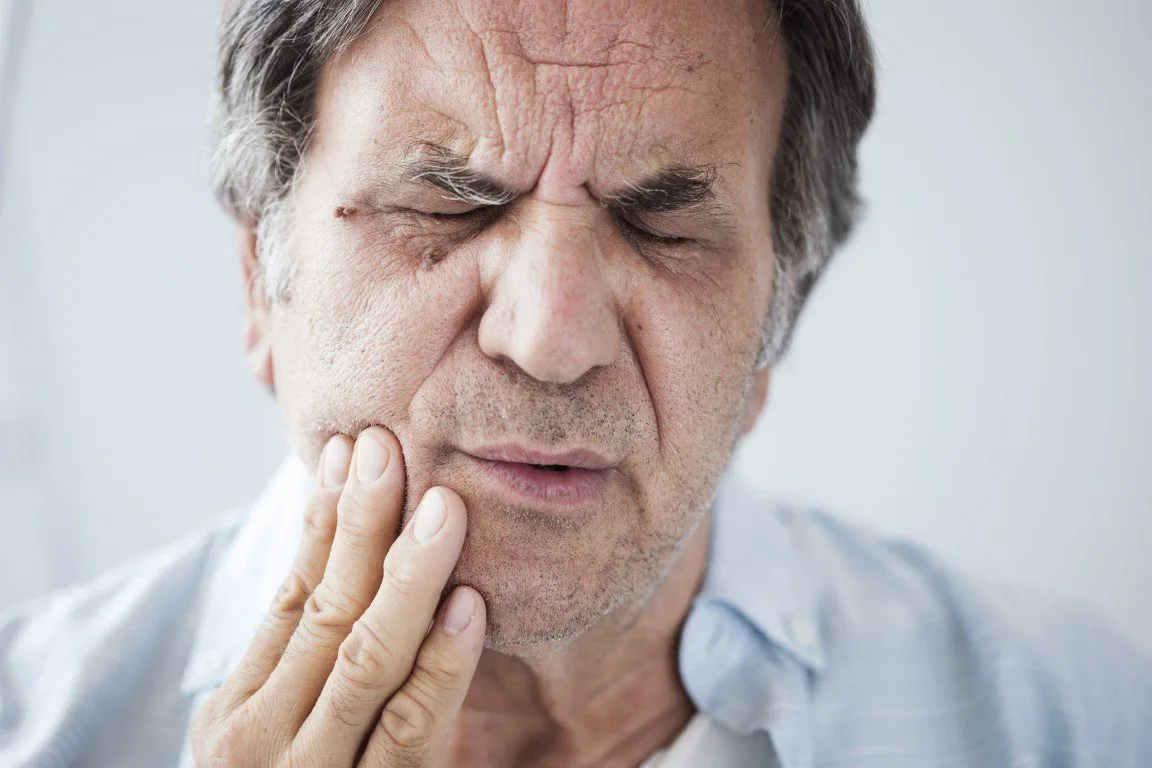 man holding his jaw and grimacing in pain